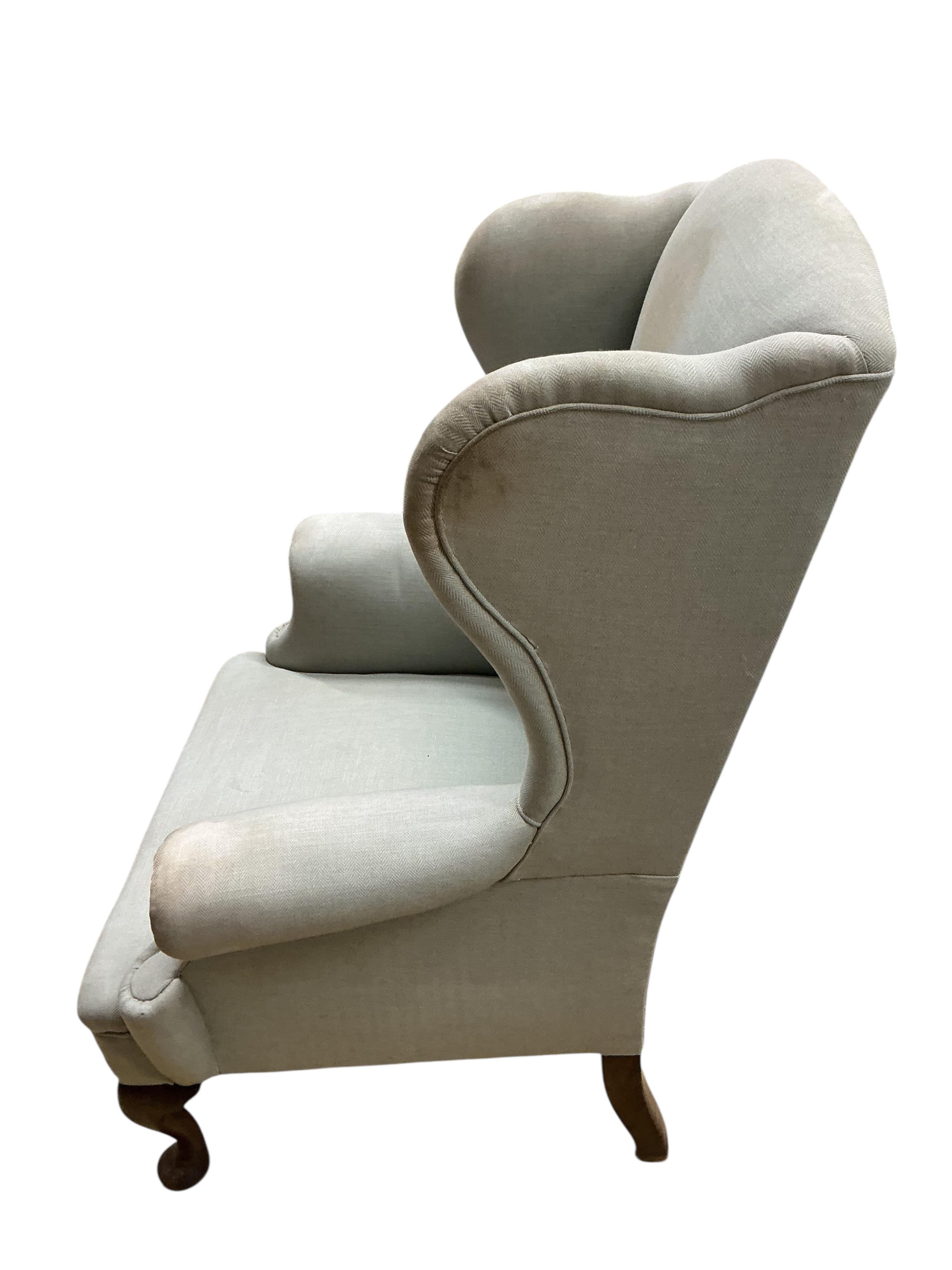 An early 20th century upholstered wing armchair, width 82cm, depth 66cm, height 108cm
